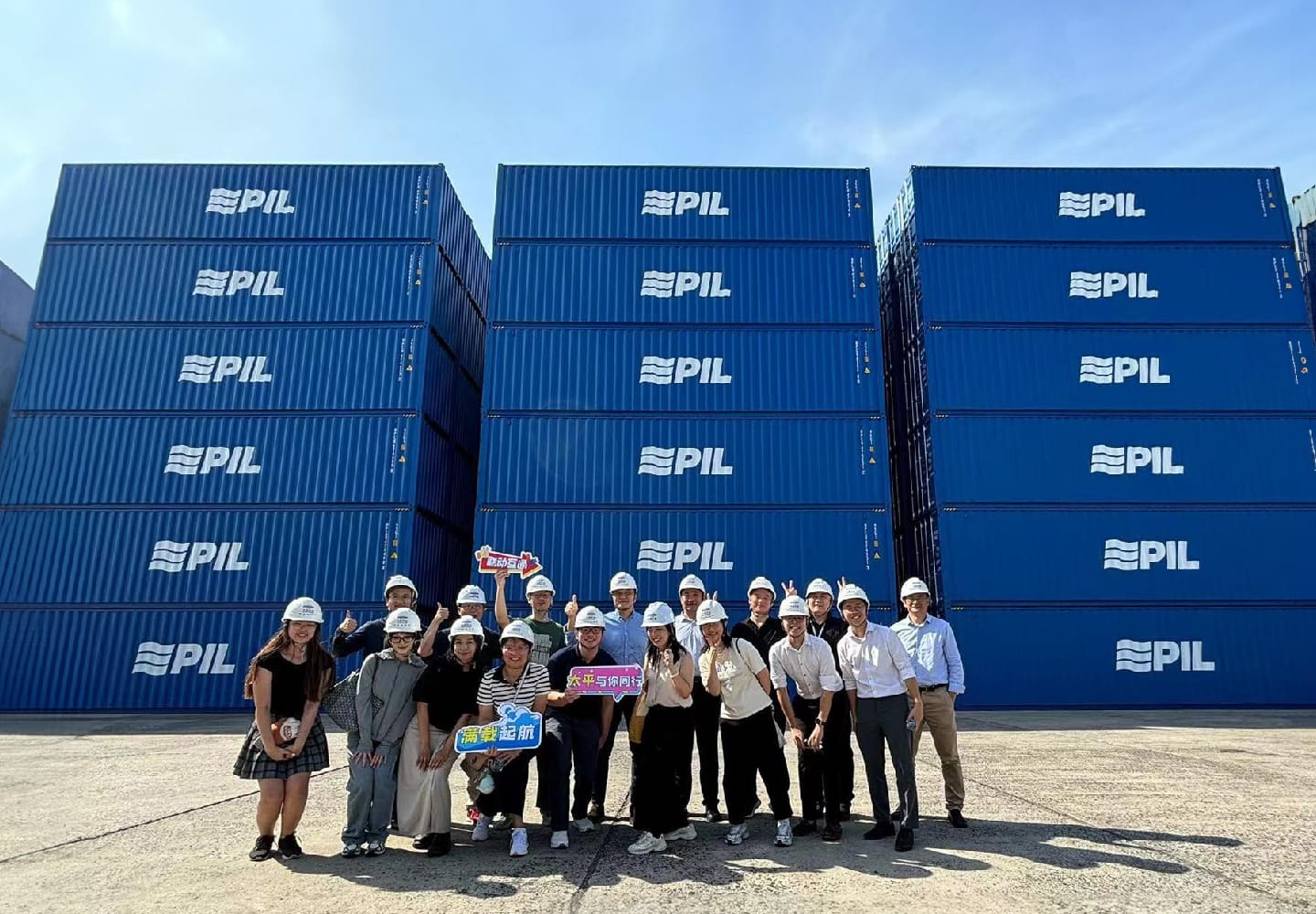 PIL team in hard hats in front of the container stacks